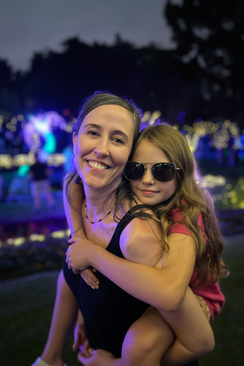 Woman and young girl hugging at a nighttime event with colorful lights in the background